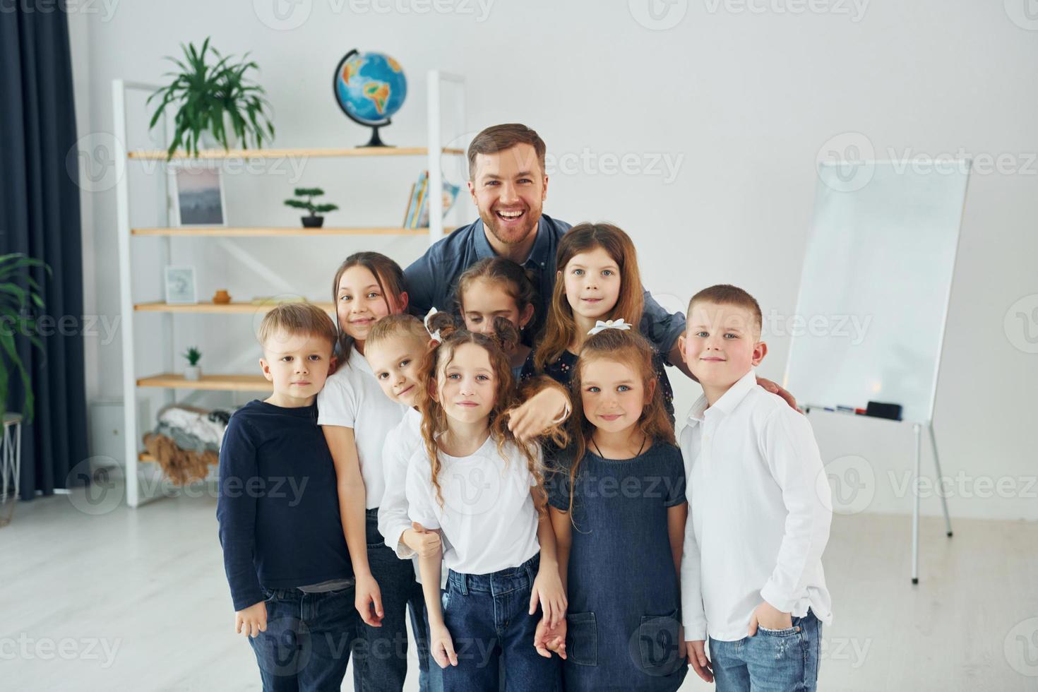 de pé juntos. grupo de alunos de crianças em sala de aula na escola com professor foto