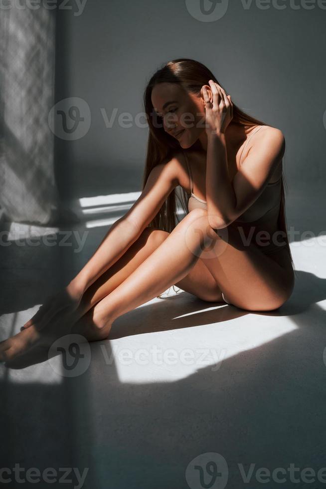 aproveitando a luz do sol. mulher de cueca com tipo de corpo magro está posando no estúdio foto