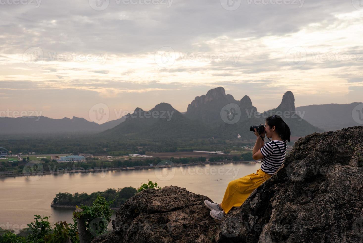 fotógrafo asiático tirando foto do pôr do sol sobre o lago e a montanha durante a viagem