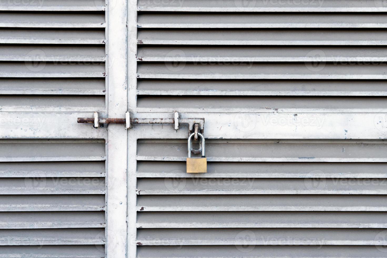 pequeno cadeado pendurado em portas de metal fechadas foto