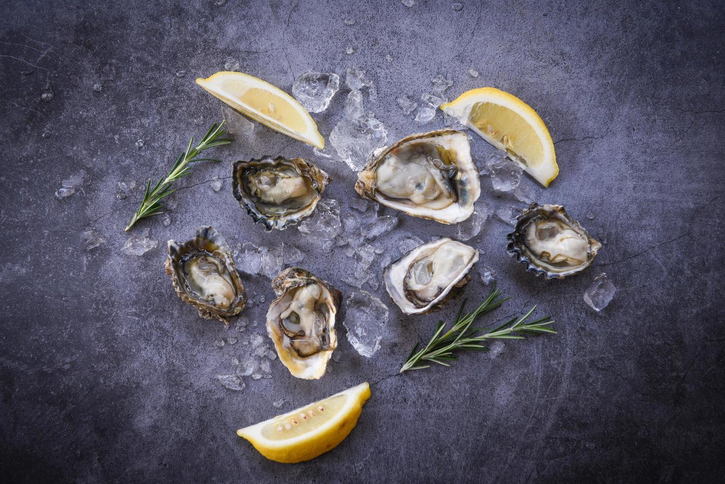 concha de ostra aberta com ervas especiarias limão alecrim servido mesa e gelo saudável frutos do mar jantar de ostras cruas no restaurante comida gourmet - ostras frescas frutos do mar no fundo da placa preta foto