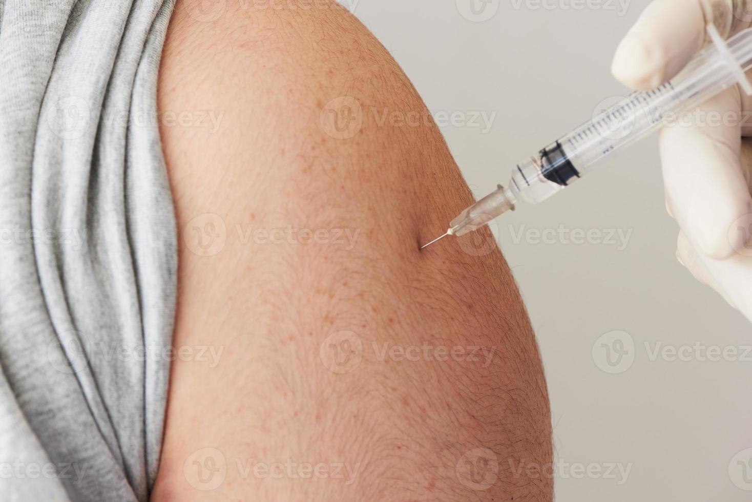 um médico injetando vacina no braço do paciente foto