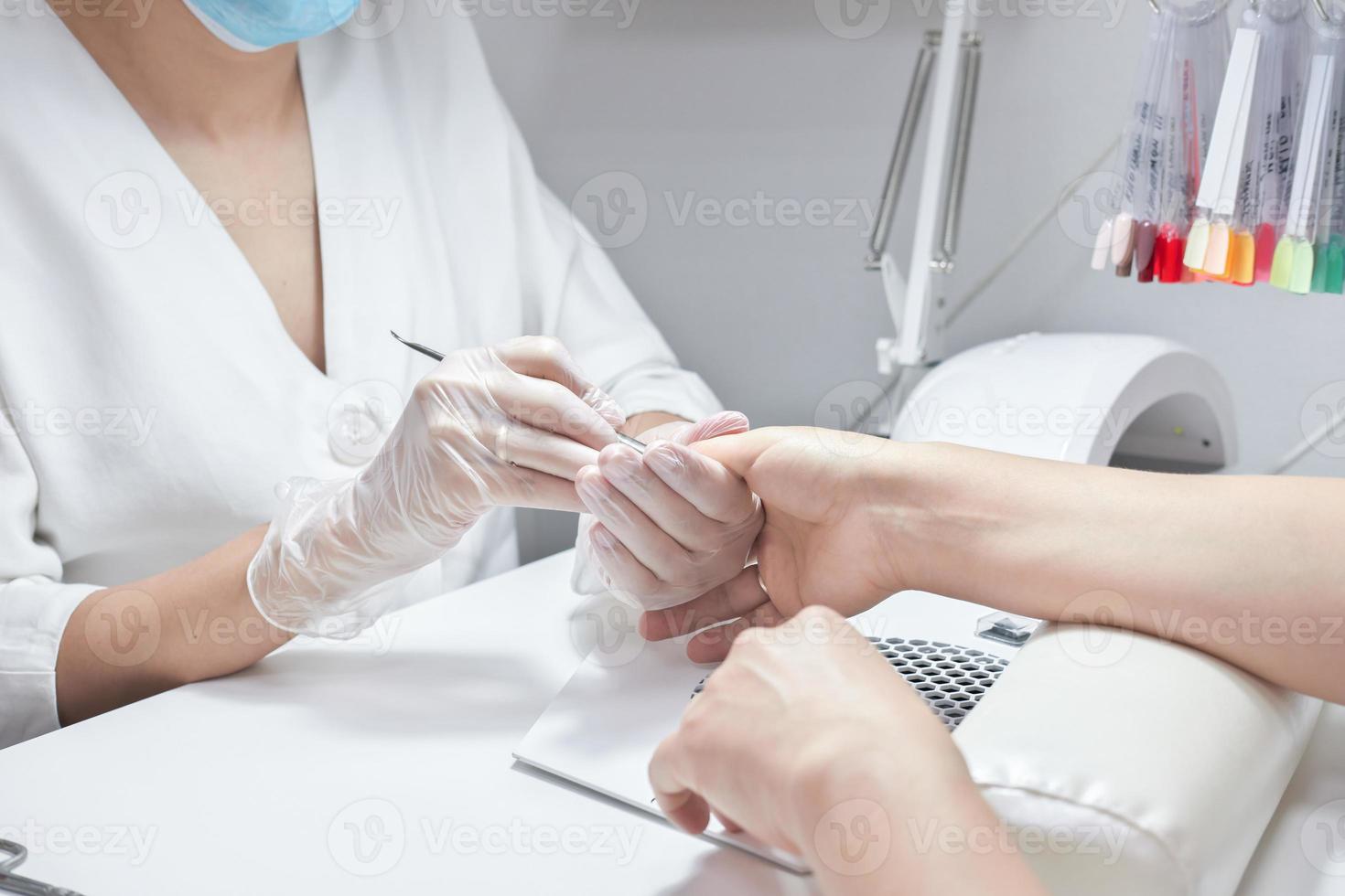 manicure profissional empurrando a cutícula na mão feminina foto