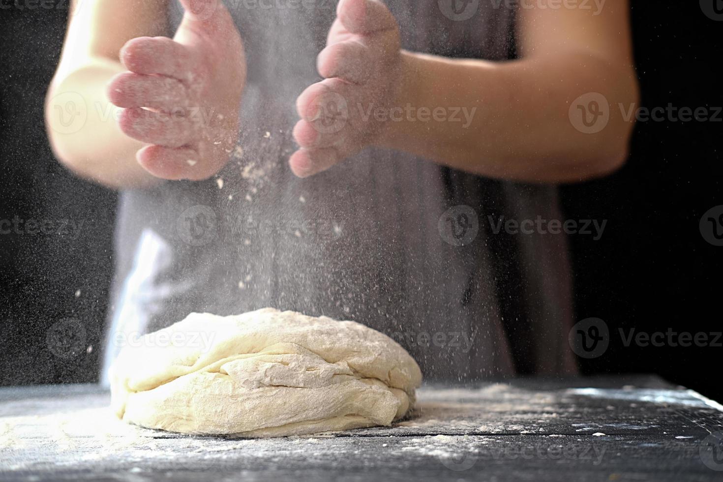 fazendo massa com as mãos na padaria ou em casa. nuvem de farinha no ar. foto