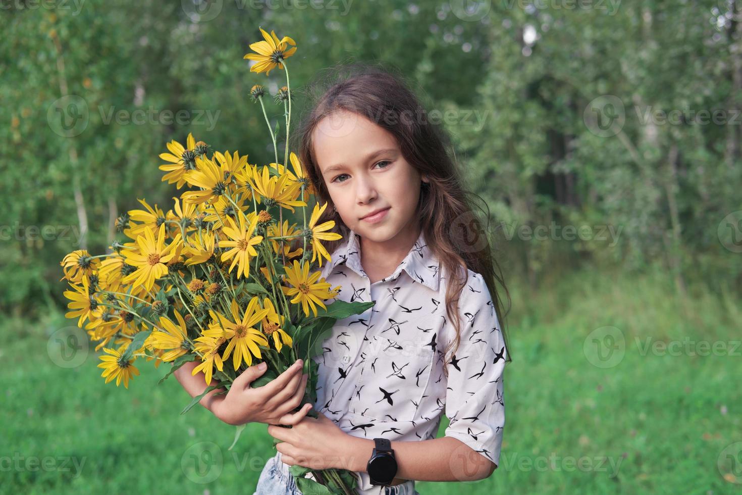 menina segurando atrás de um buquê de flores de topinambur. foto