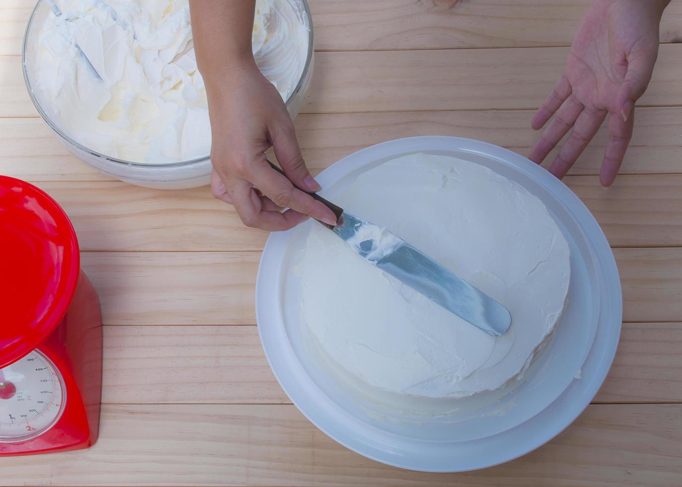 colocando o bolo de creme de manteiga à mão usando espátula foto