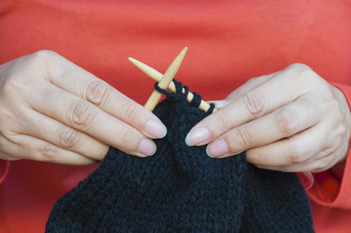 as mãos da mulher estão fazendo tricô de chapéu preto foto