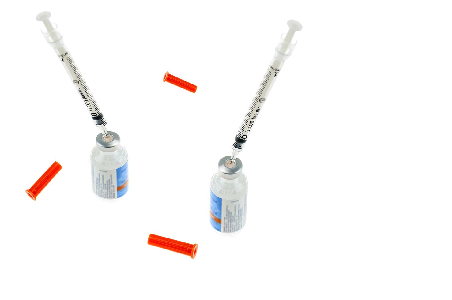 seringa e frasco de insulina isolado sobre fundo branco. a foto está focada na área da agulha.
