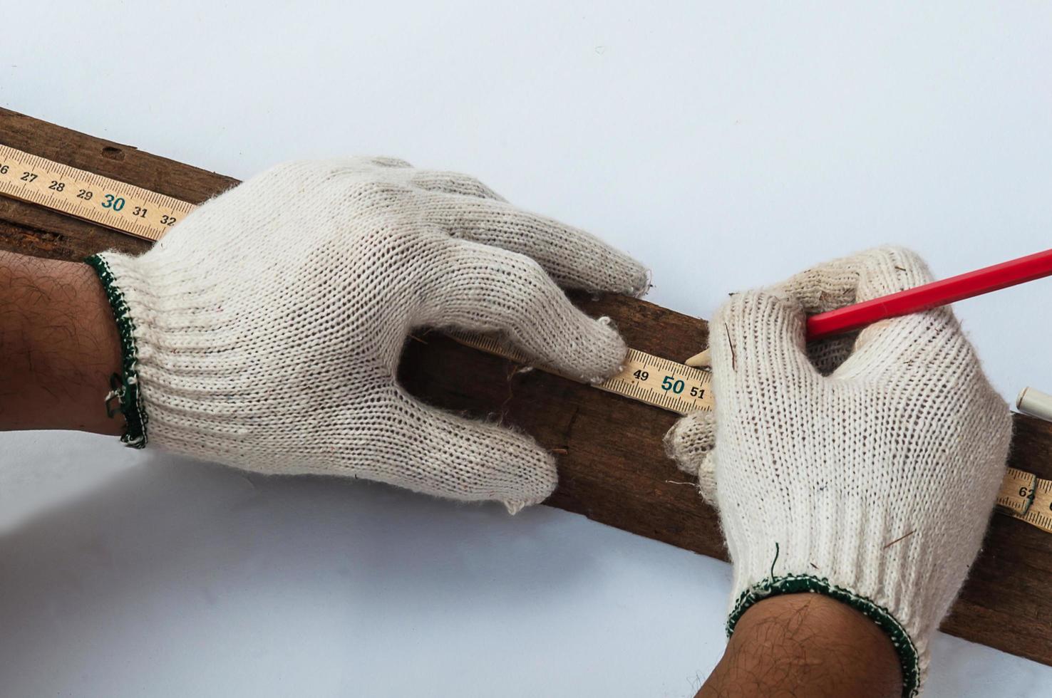 mãos de carpinteiro usando régua dobrável de madeira para medir seu trabalho de corte de madeira foto