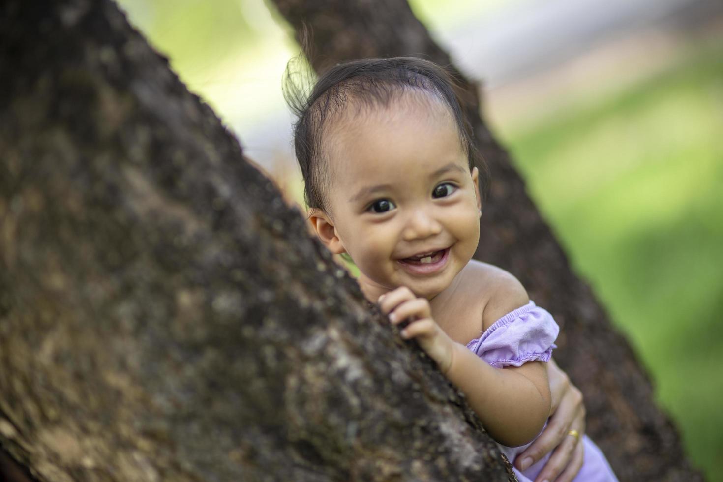 menina olhando por trás de uma árvore de bétula foto