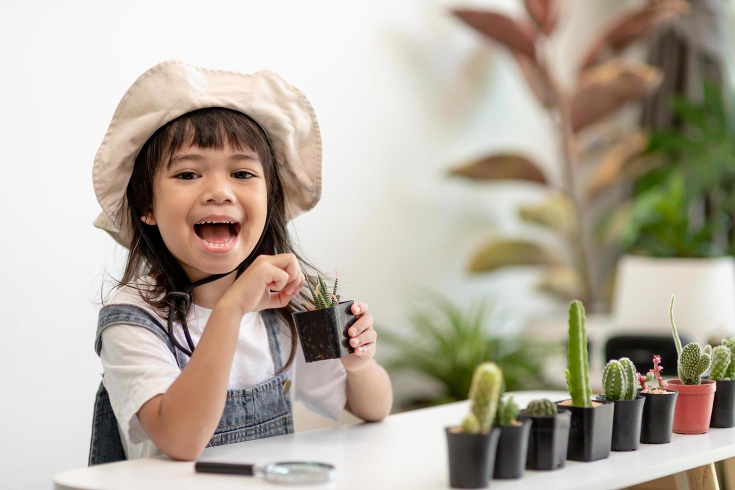 garoto toque suavemente o novo caule do cacto que ele cresce com cuidado, uma mão segura o conceito de habilidades de educação, montessori e observação de ampliação glass.nature. foto