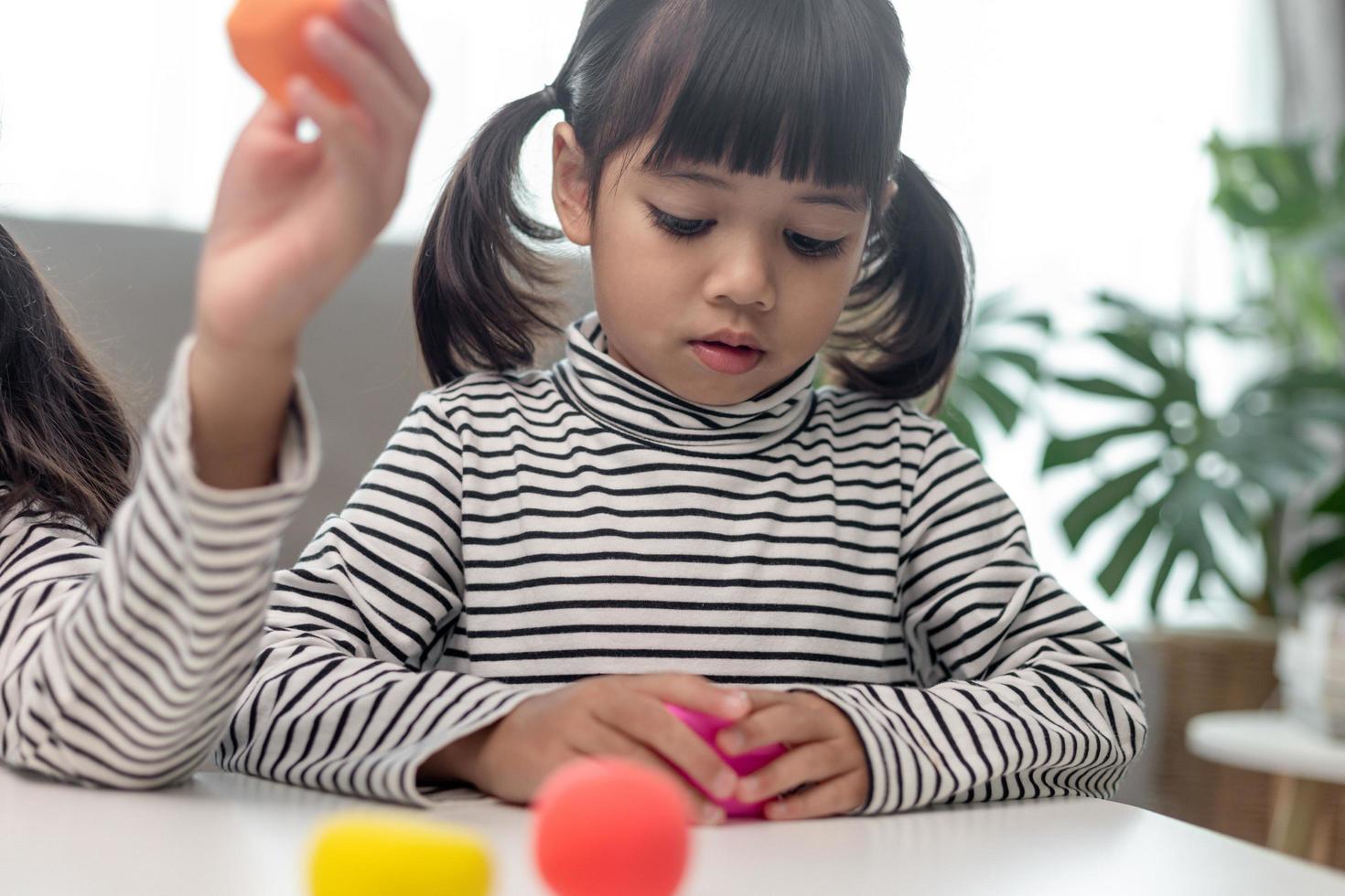 a menina está aprendendo a usar massinha colorida em uma sala bem iluminada foto