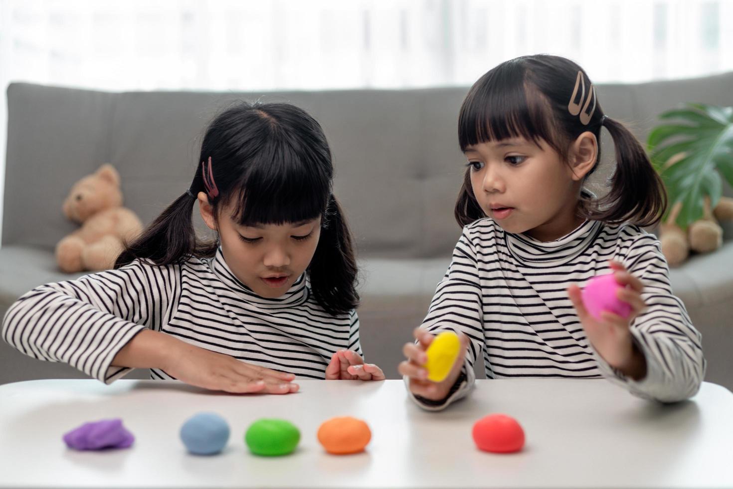 a menina está aprendendo a usar massinha colorida em uma sala bem iluminada foto