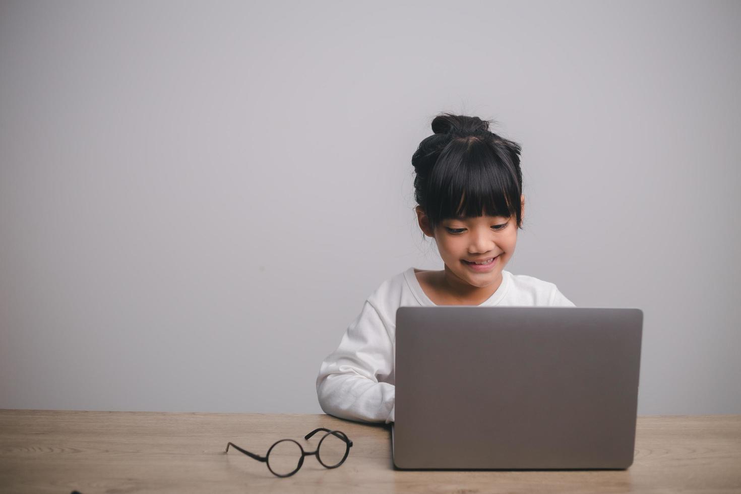 estudante de criança asiática de volta à escola ou sorriso de menina criança escreva uma nota ou desenhe a lápis e leia em um tablet de computador fazendo lição de casa para uma nova ideia pensar ou as pessoas aprendem em casa foto