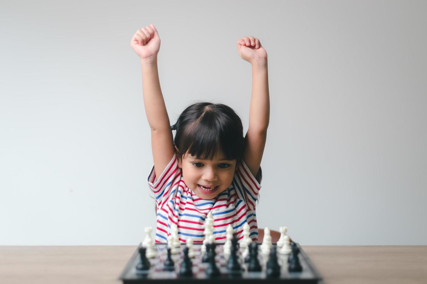 menina asiática jogando xadrez em casa. um jogo de xadrez foto