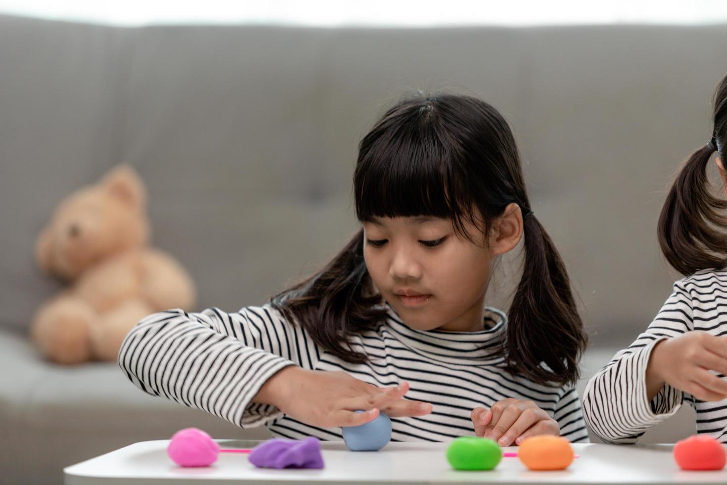 a menina está aprendendo a usar massinha colorida em uma sala bem iluminada foto