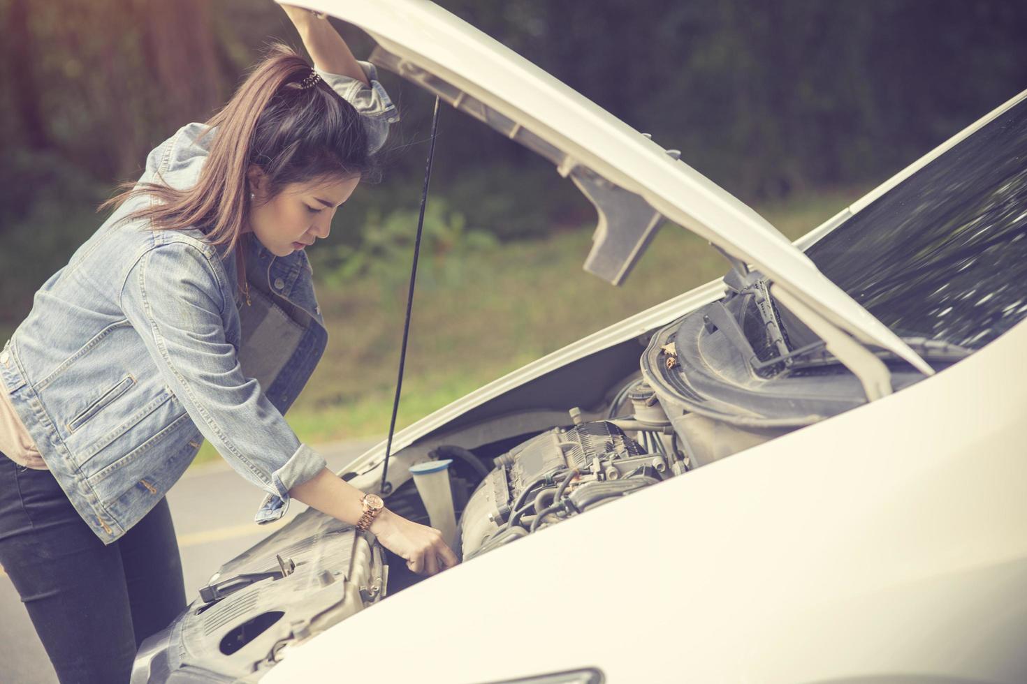 mulheres especulam que ela abriu o capô do carro quebrado na lateral ver motores que estão danificados ou não foto