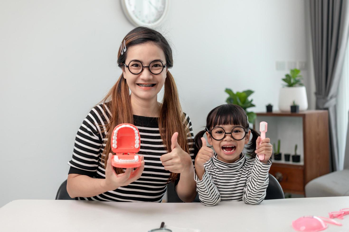 mãe ensinando filha criança escovando os dentes em casa foto