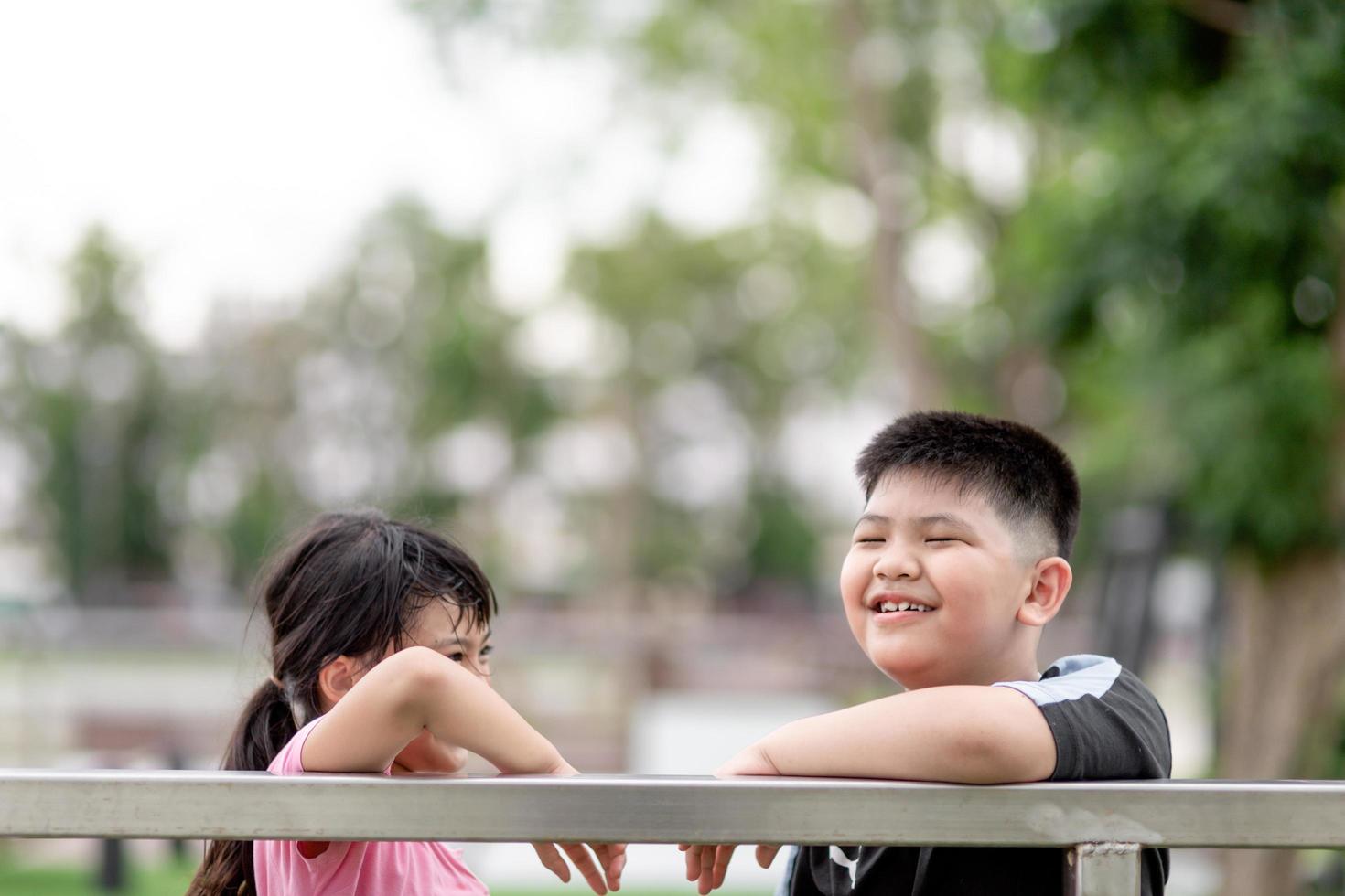 duas crianças asiáticas menino e menina felizes e sorriam no parque foto