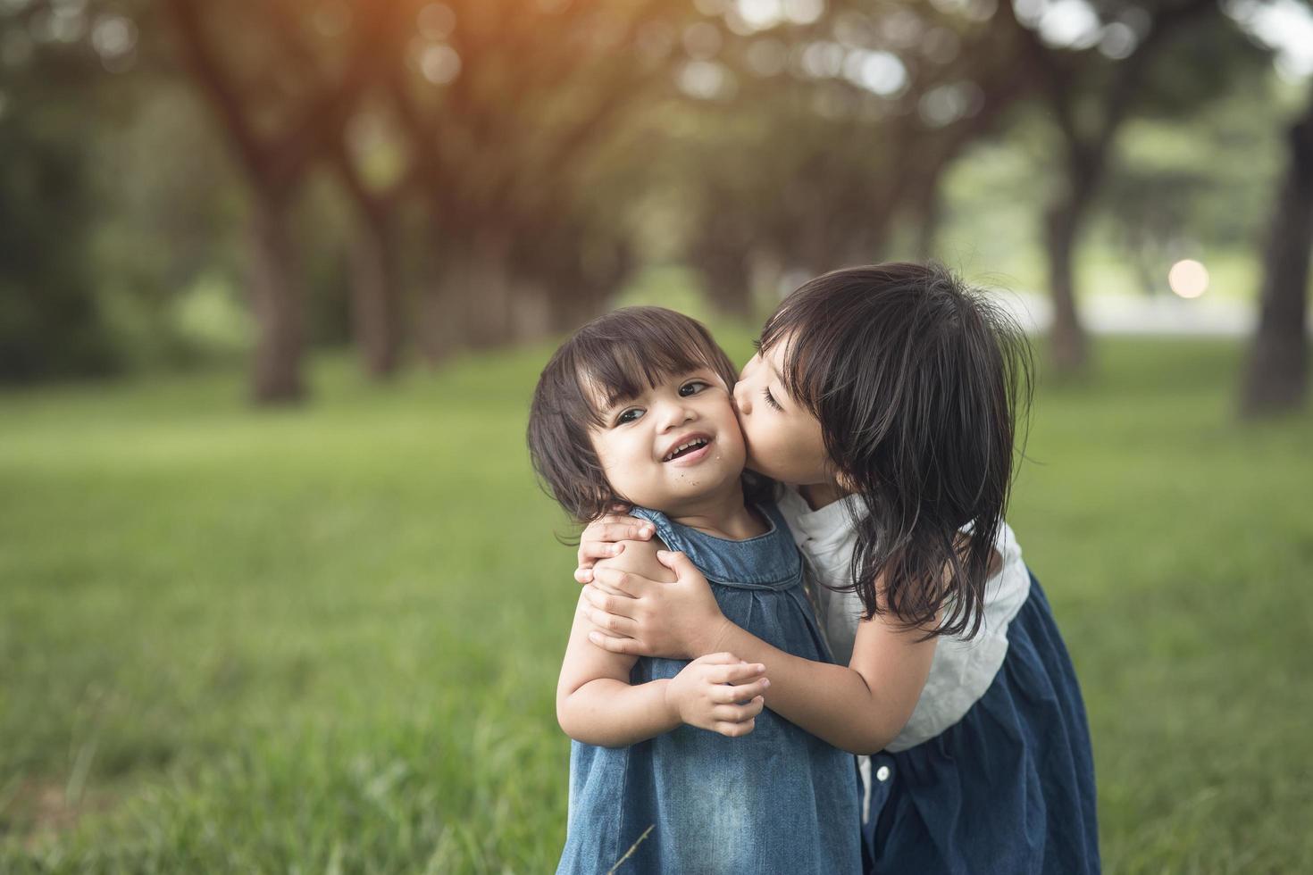 família feliz. irmãzinhas se beijando e rindo no verão ao ar livre foto