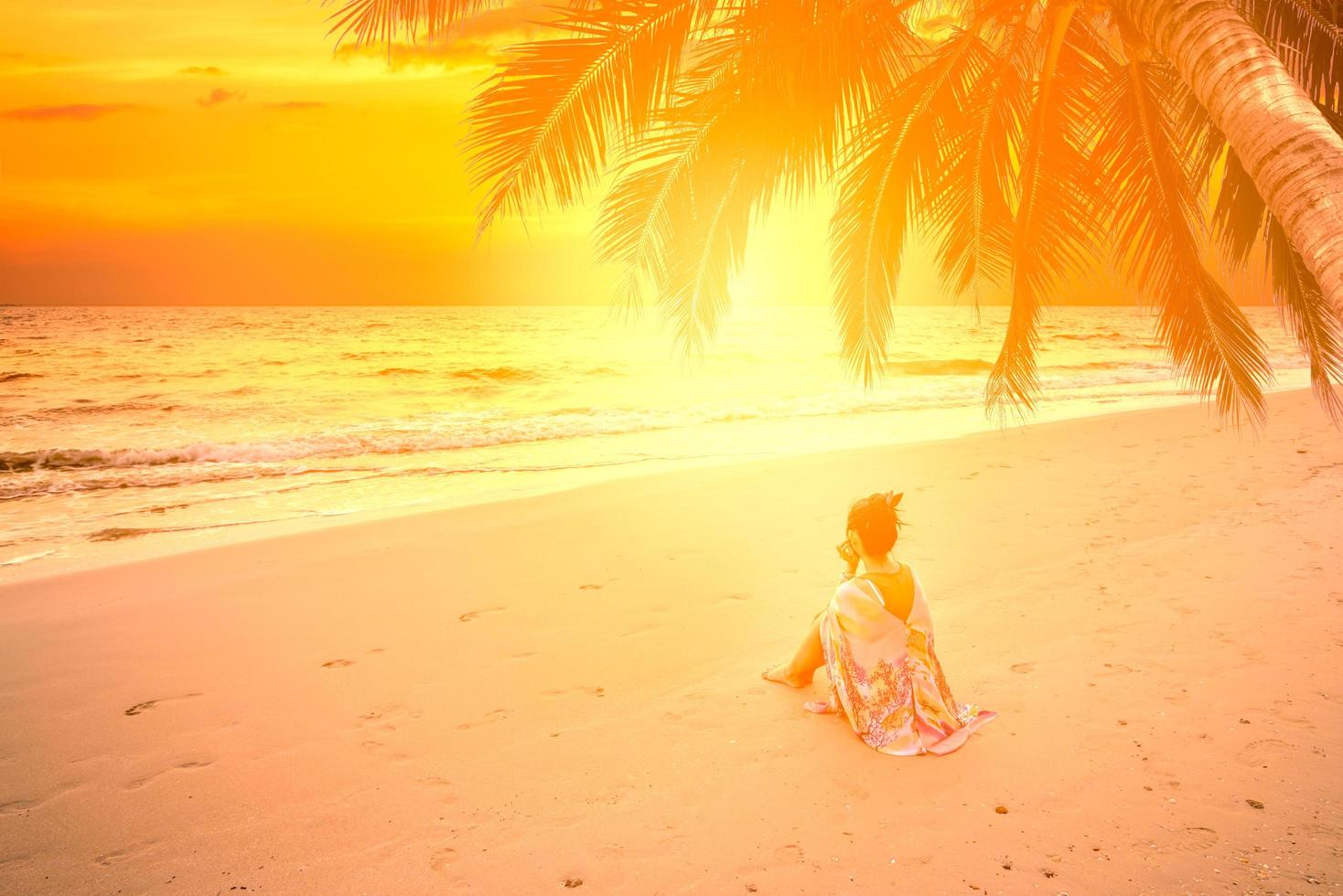 jovem fêmea sentada na praia tropical e relaxando no verão foto