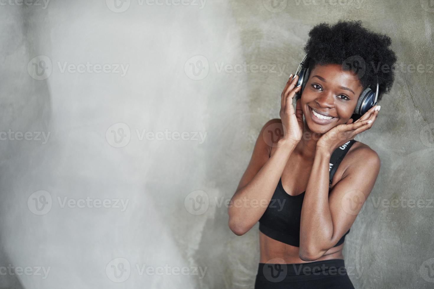 olhando para a câmera. retrato de garota afro-americana em roupas de fitness tendo uma pausa após o treino foto