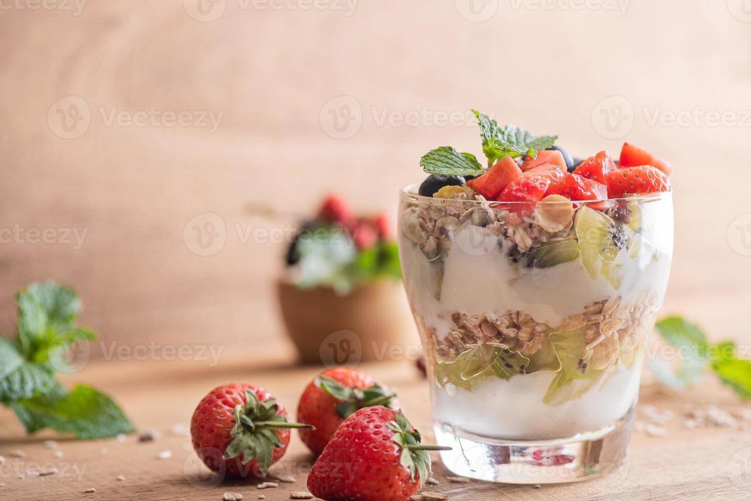 muesli caseiro, tigela de granola de aveia com iogurte, mirtilos frescos, amora, morangos, kiwi, hortelã e nozes placa para café da manhã saudável, copie o espaço. conceito de café da manhã saudável. comer limpo. foto