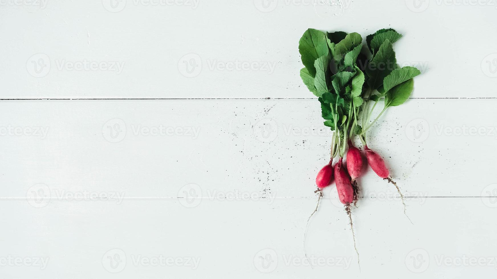 bando fresco de rabanetes em um fundo branco de madeira foto