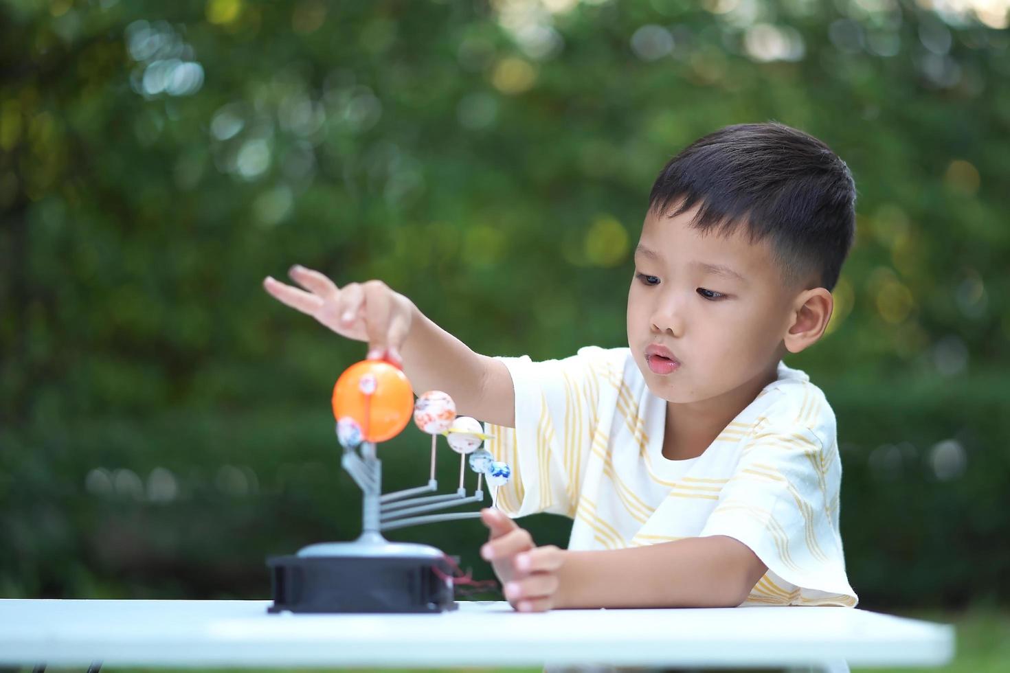 menino asiático vivendo brinquedos do sistema solar, equipamento de aprendizagem em casa, durante nova mudança normal após coronavírus ou situação de pandemia de surto pós covid-19 foto