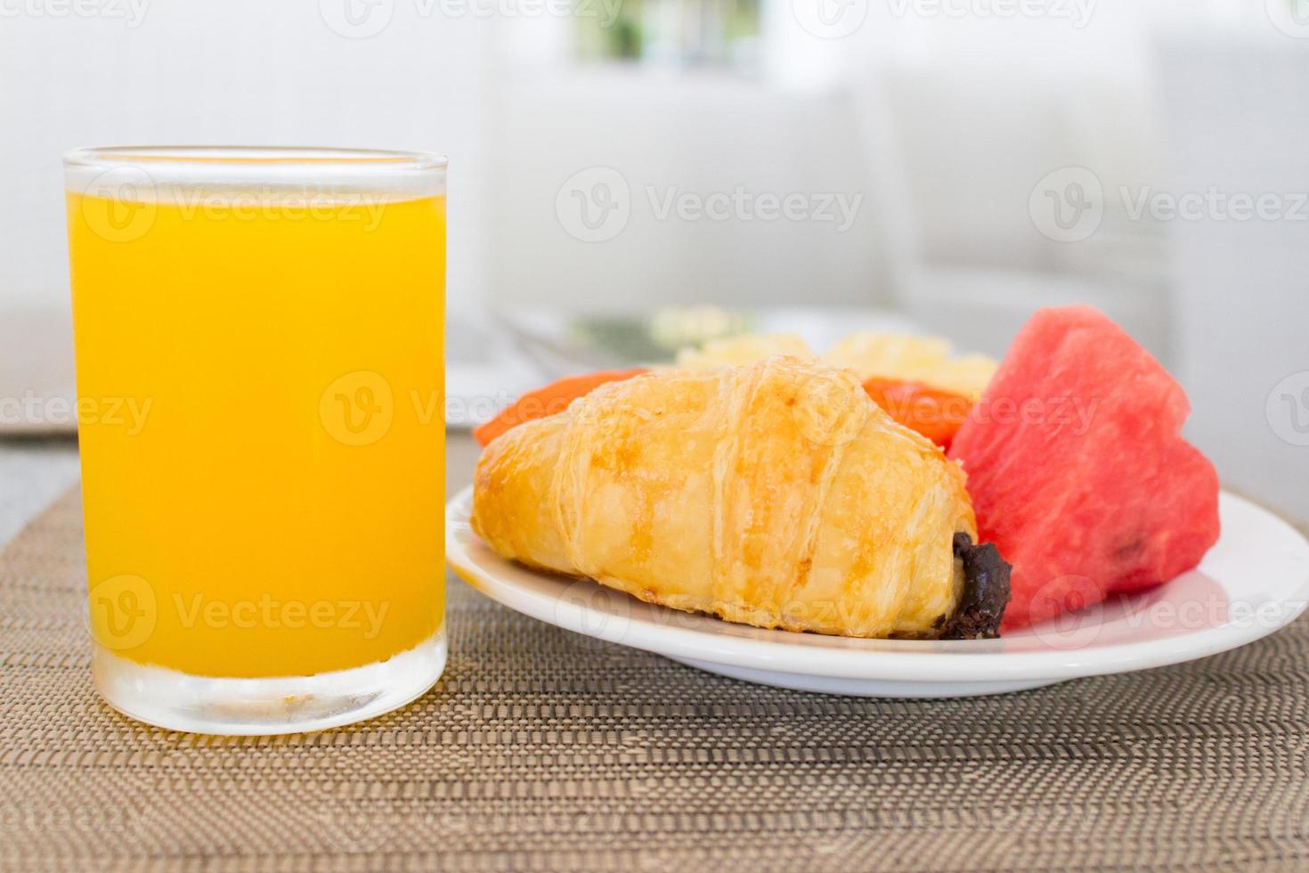 café da manhã com suco de laranja, croissant e frutas foto