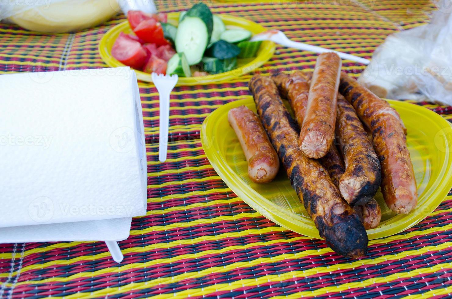 salsichas grelhadas e legumes frescos em um piquenique. foto