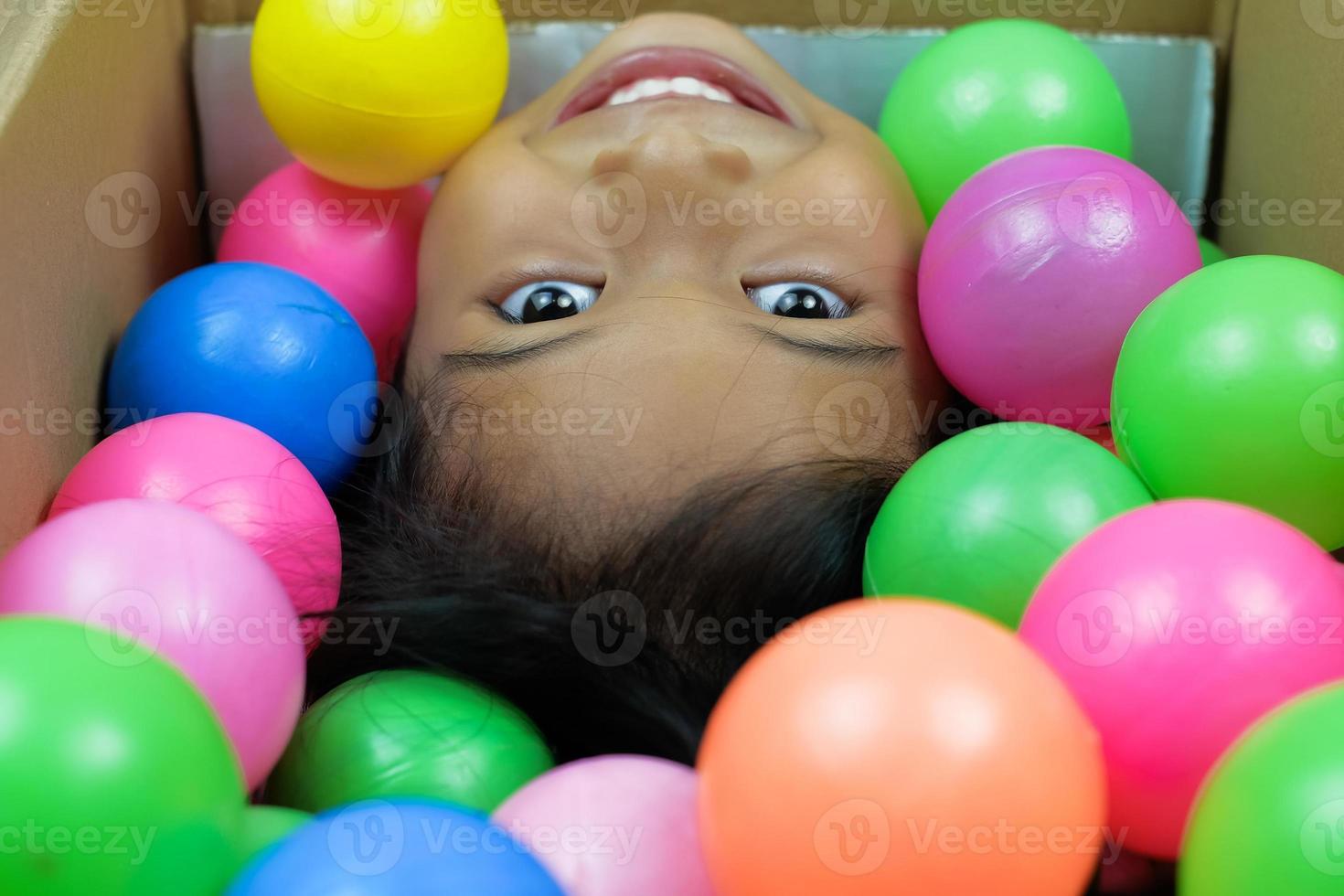 uma garota sorrindo amplamente jogando na bola colorida foto