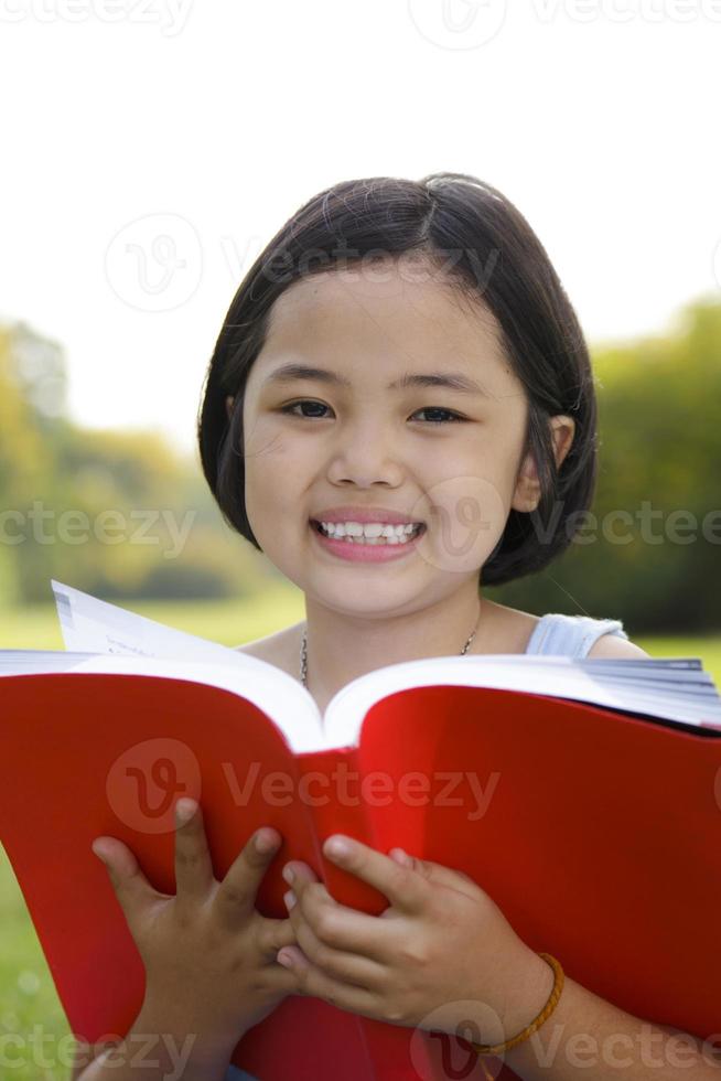 menina asiática lendo livro no parque foto