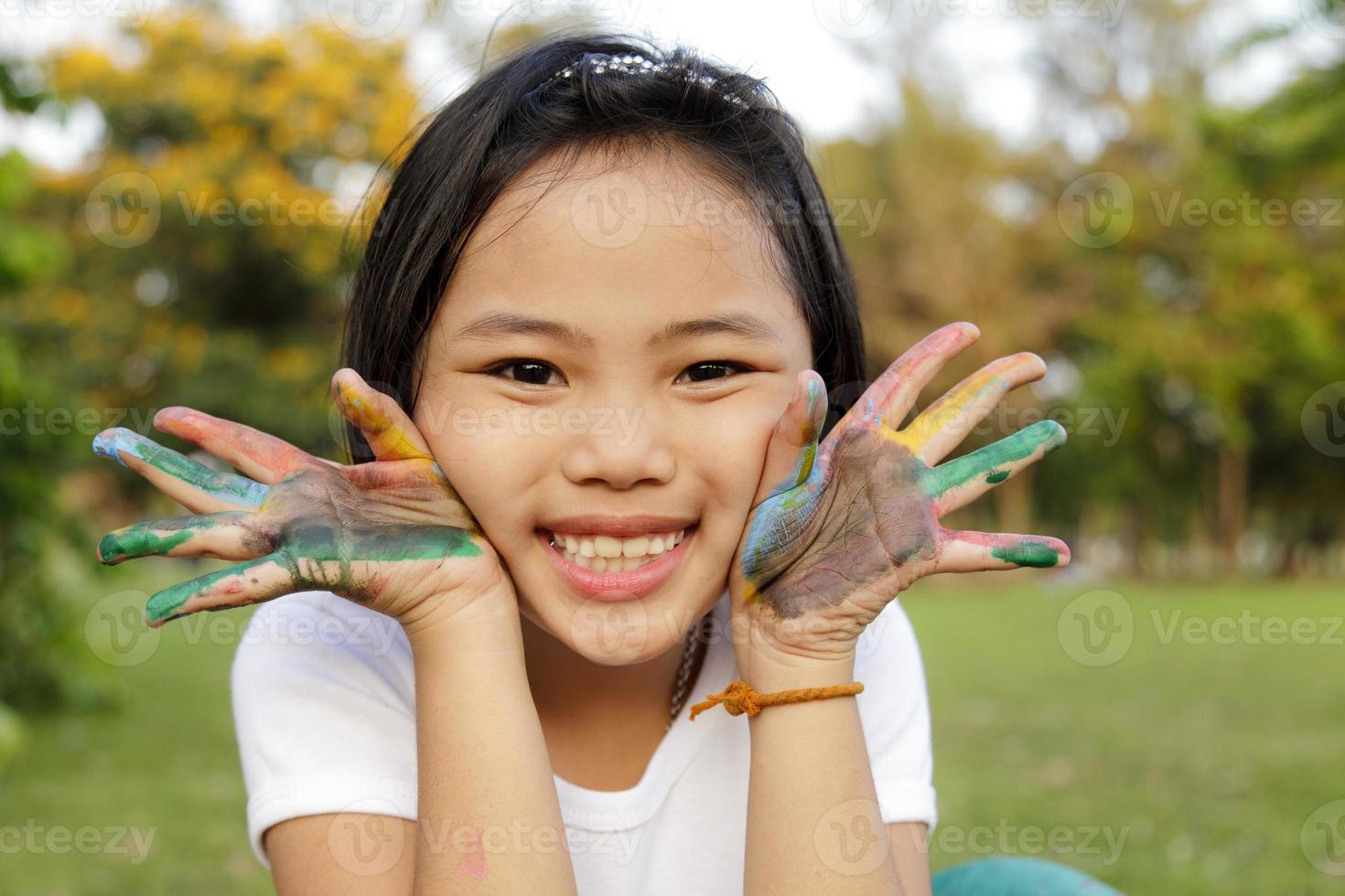 menina asiática com as mãos pintadas em tintas coloridas foto