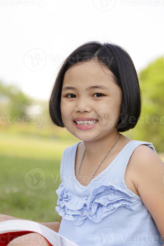 menina asiática lendo livro no parque foto