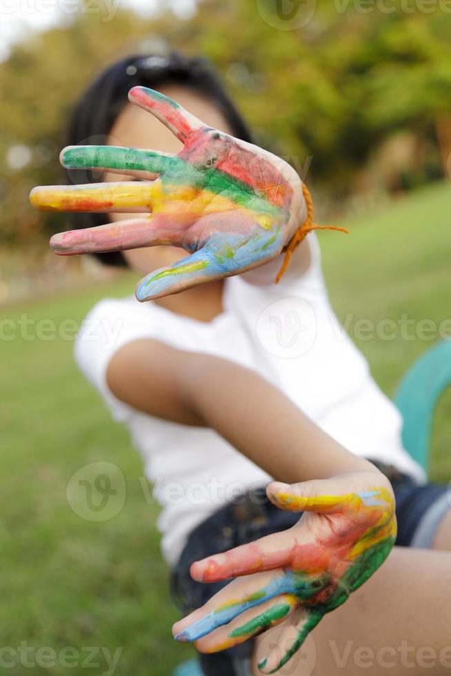 menina asiática com as mãos pintadas em tintas coloridas foto