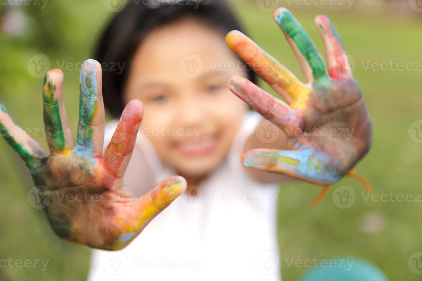 menina asiática com as mãos pintadas em tintas coloridas foto