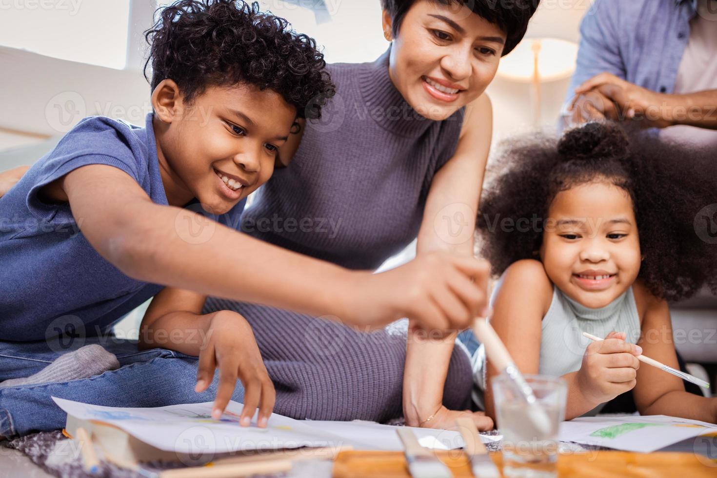 feliz família afro-americana com crianças pintando juntos em casa foto