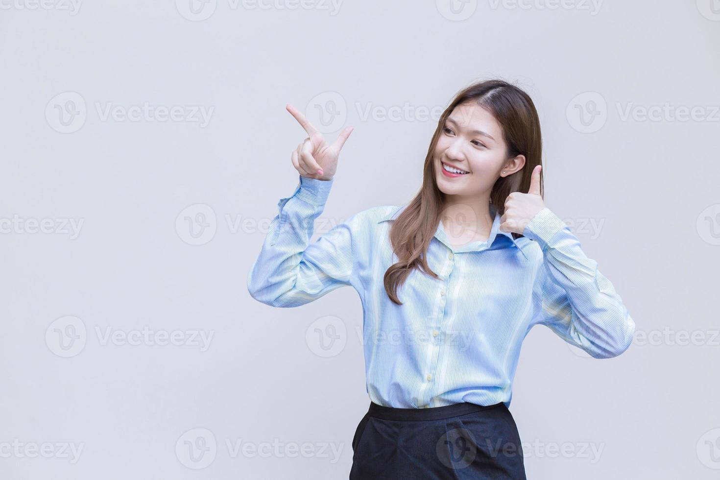 mulher de negócios profissional asiática que tem cabelos compridos com uma camisa azul sorri apresenta algo sobre um fundo branco. foto