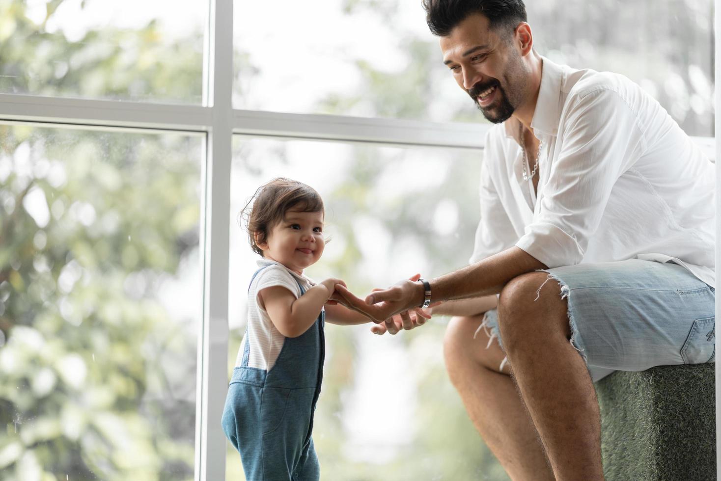 criança bonitinha conceito de família criança, bebê aprendendo a andar com pai e mãe para ajudar a cuidar e segurar a mão, primeiro passo com apoio dos pais na infância, pequeno retrato de amor menino em casa foto