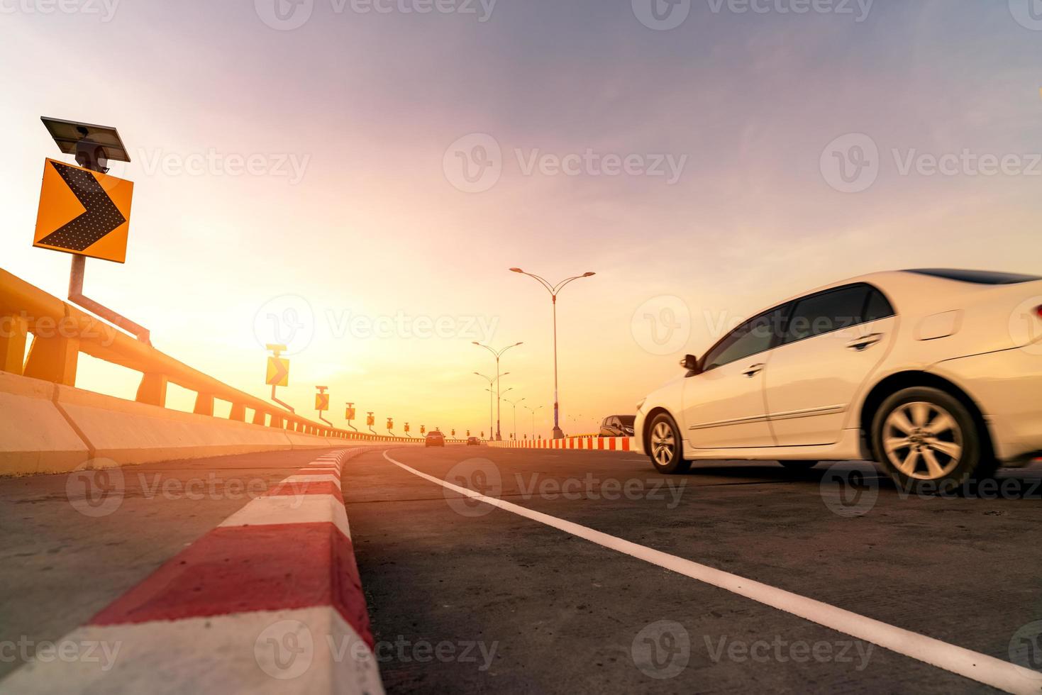 borrão de movimento do carro branco dirigindo na estrada de concreto curva com sinal de trânsito. viagem nas férias de verão. carro na rua. viagens de verão de carro. energia do painel solar no sinal de tráfego de curva amarela foto