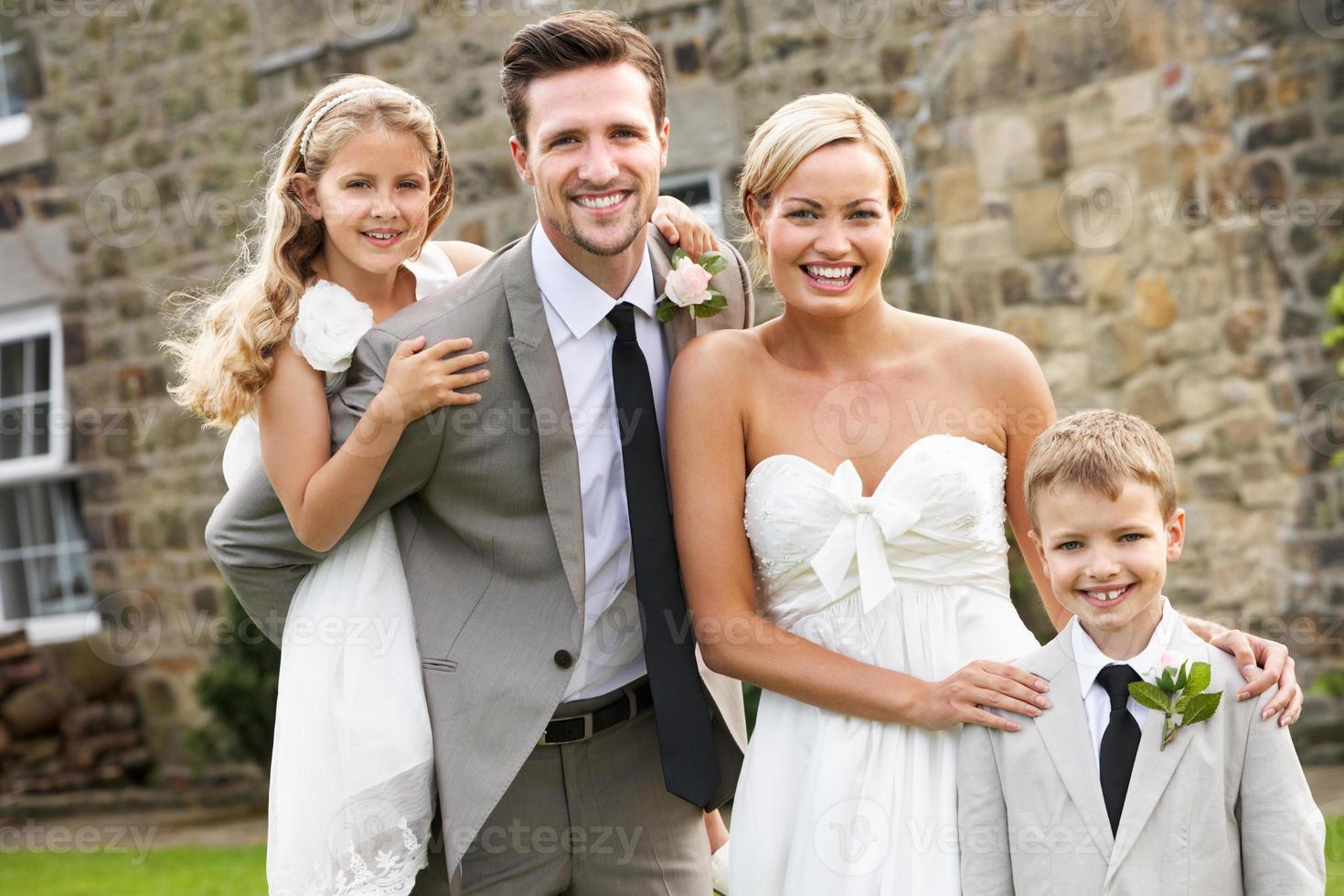 casal recém-casado com dama de honra e menino de página no casamento foto