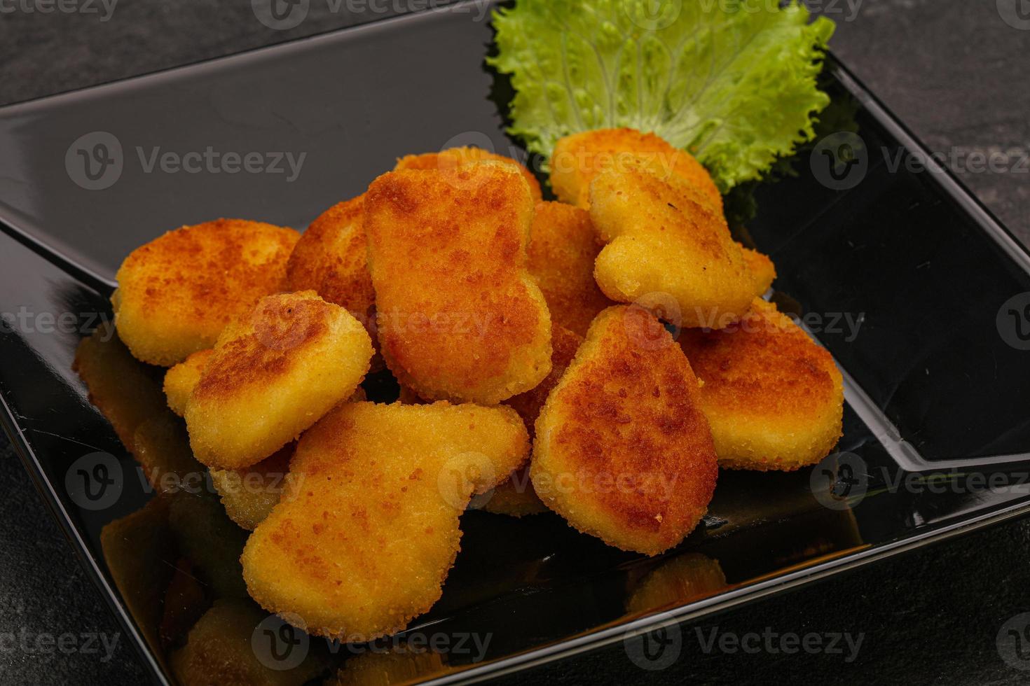 nuggets de frango frito servido com folhas de salada foto