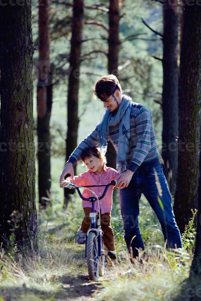 pai aprendendo seu filho a andar de bicicleta fora em foto