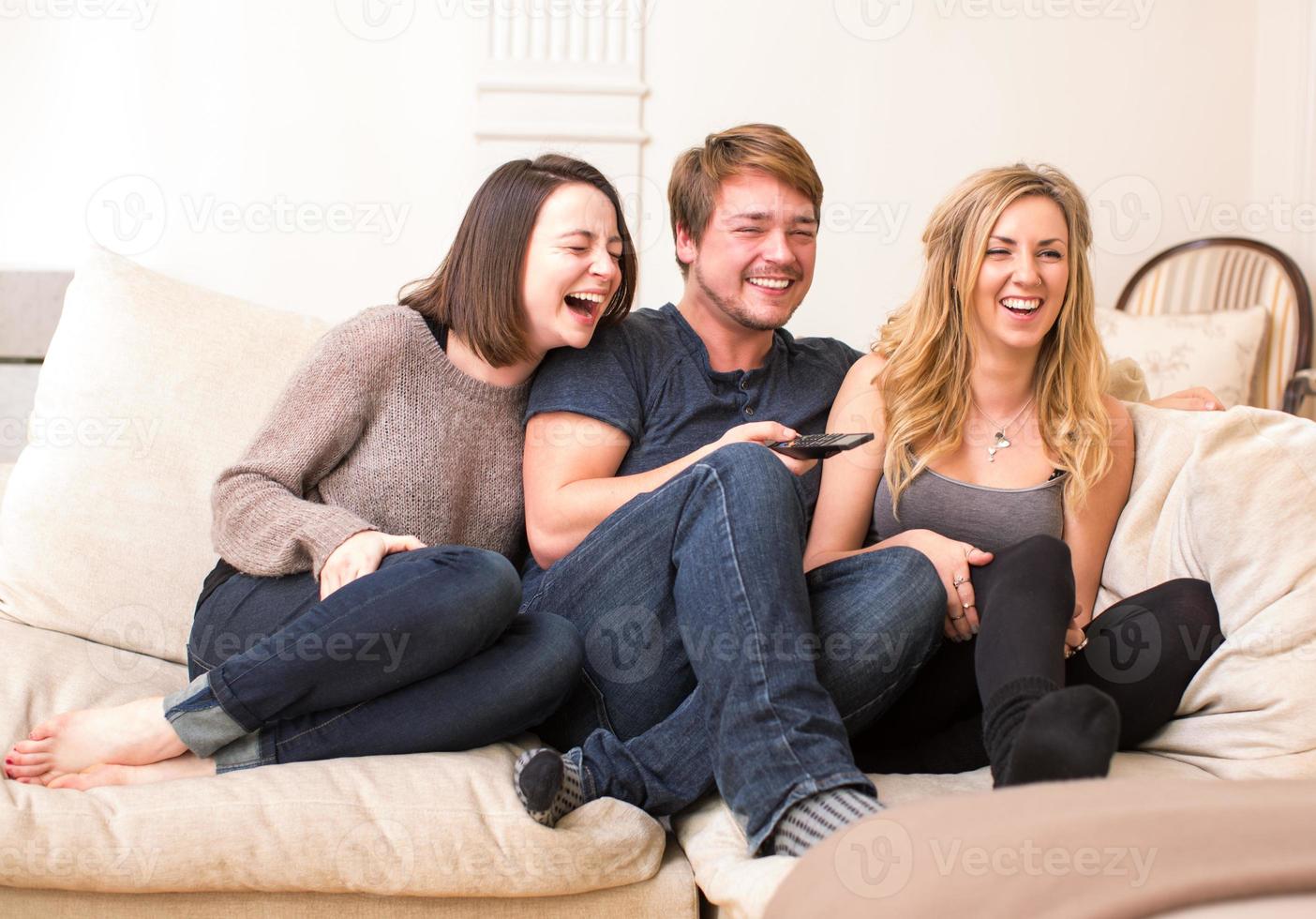 três adolescentes desfrutam de um programa de televisão engraçado foto