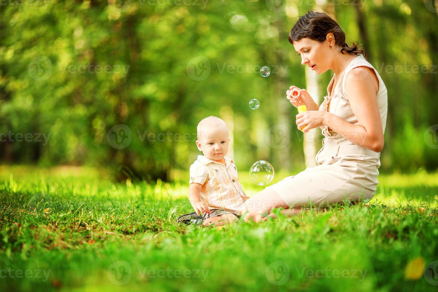 mãe e bebê soprando bolhas no parque. foto