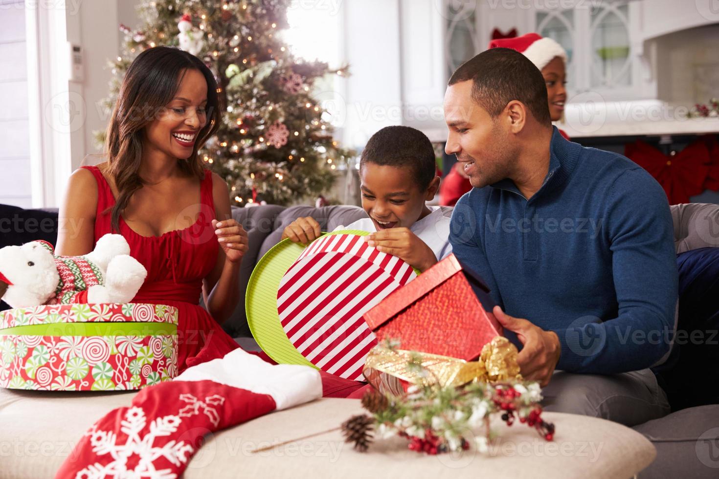 família abrindo presentes de Natal em casa juntos foto