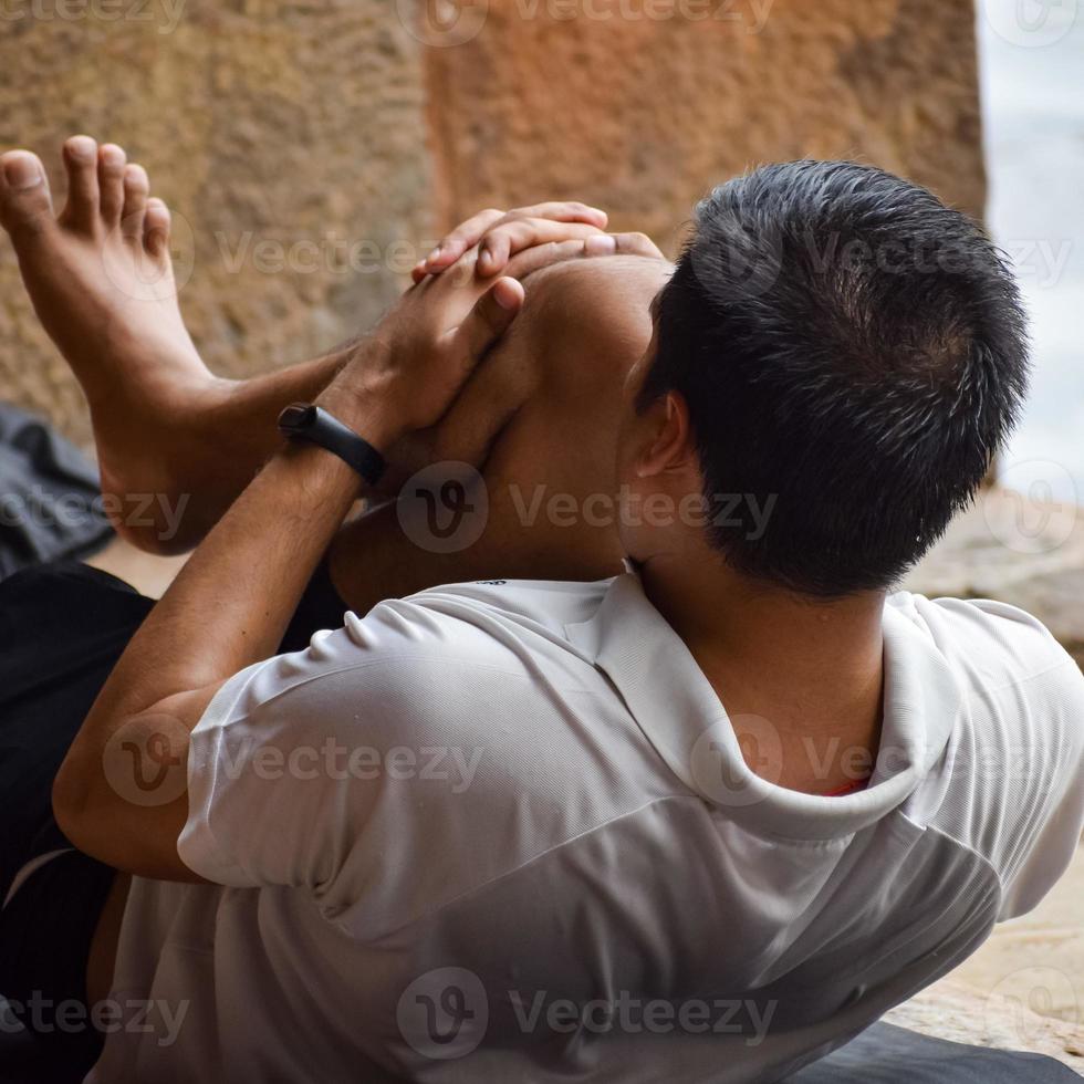 inspirado jovem indiano fazendo yoga asanas em lodhi garden park, nova delhi, índia. jovem cidadão se exercitando fora e em pé em pose de ângulo lateral de ioga. fitness ao ar livre e conceito de equilíbrio de vida foto