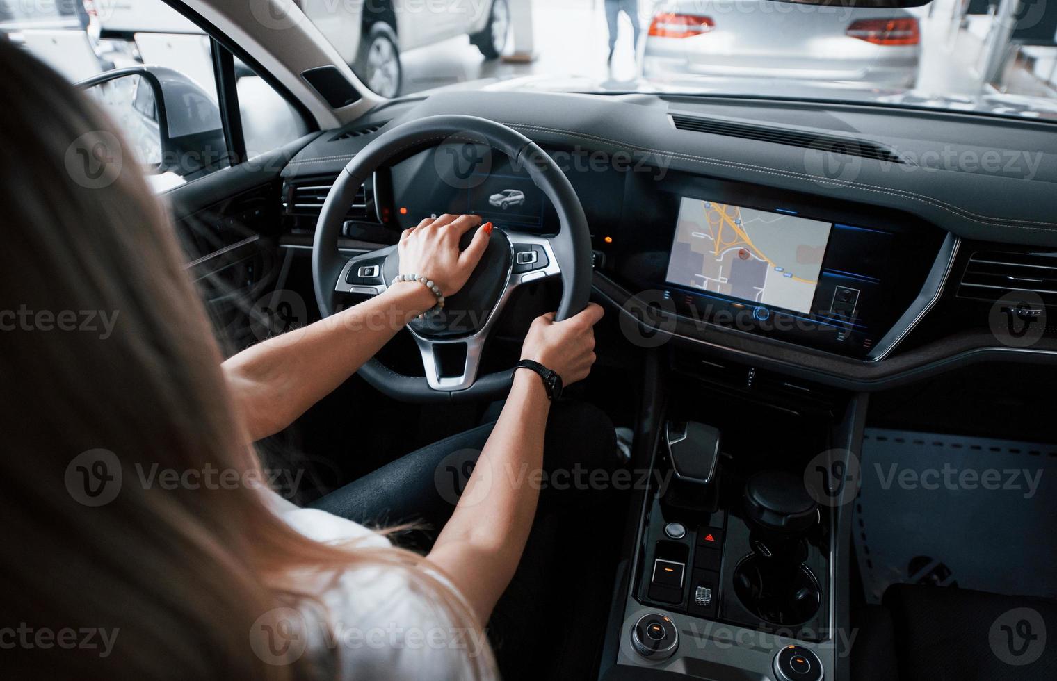 usando gps. garota no carro moderno no salão. durante o dia dentro de casa. compra de veículo novo foto