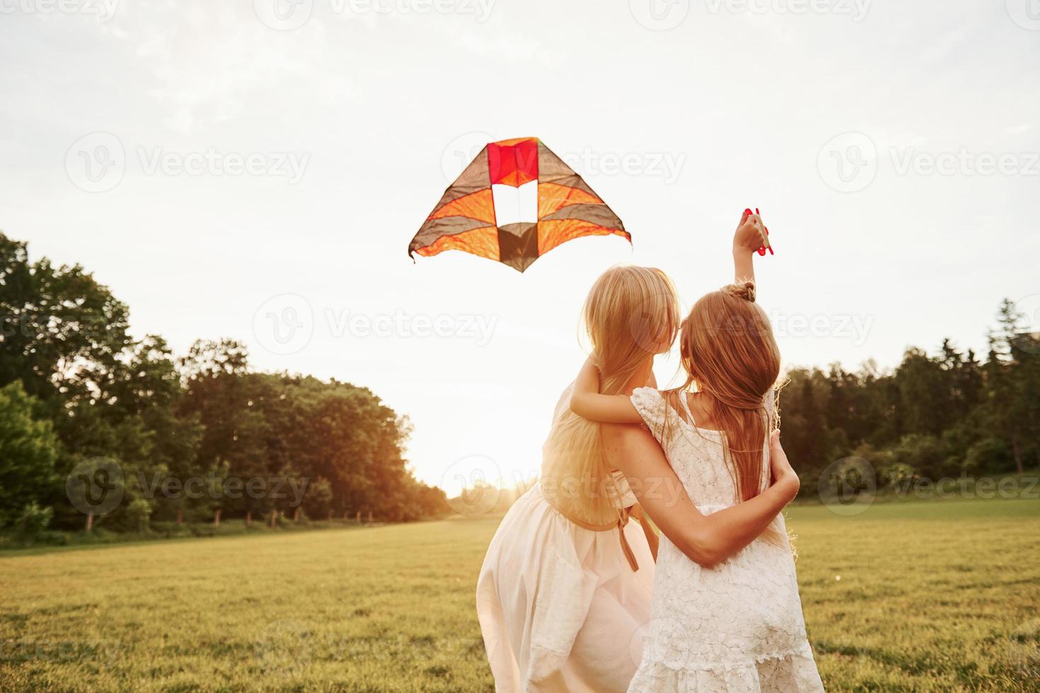 o que é isso no céu. mãe e filha se divertem com pipa no campo. natureza bela foto